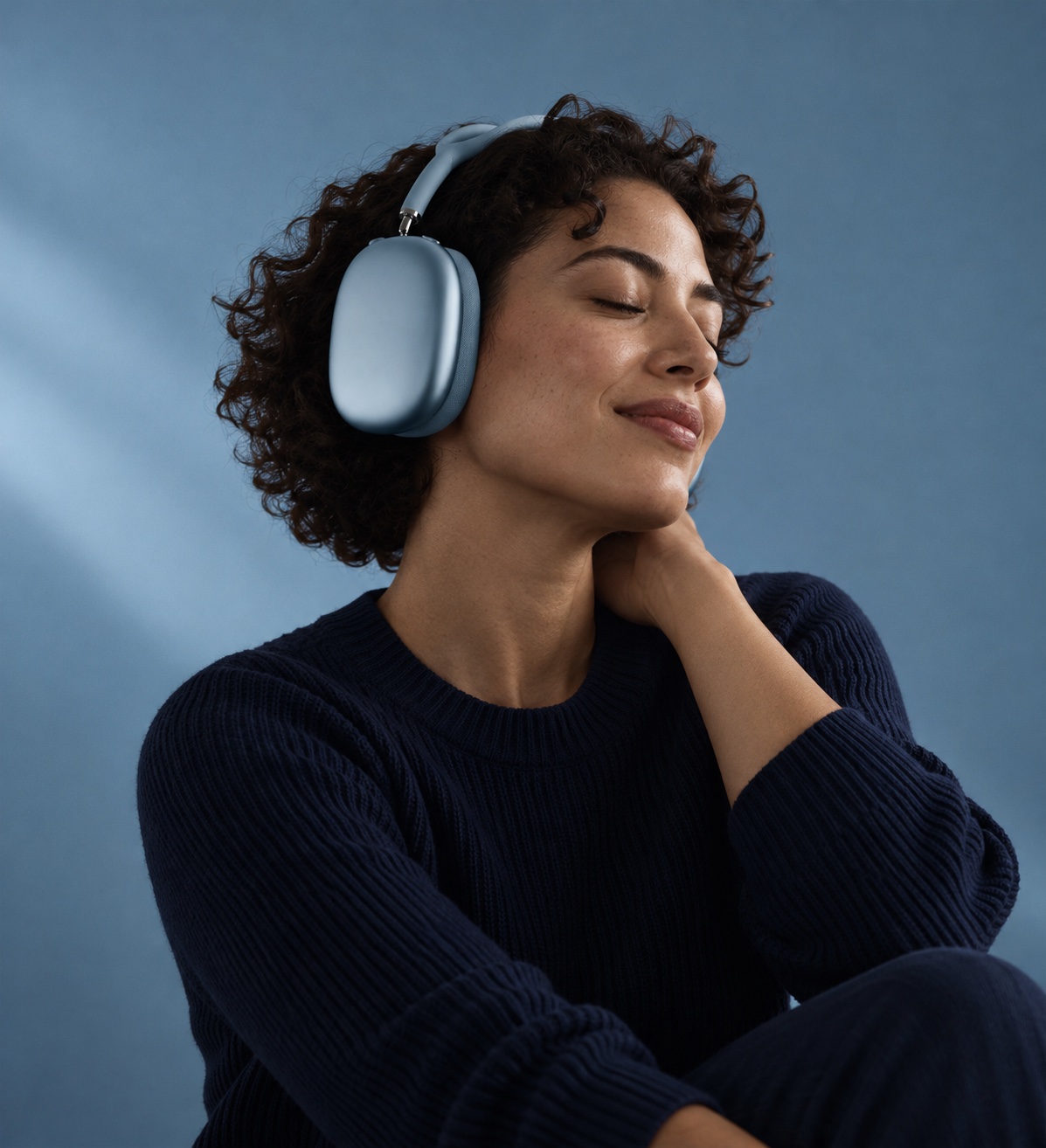 블루 색상 AirPods Max 2 헤드폰을 착용한 채 눈을 감고 고개를 기울인 사람의 옆모습.
